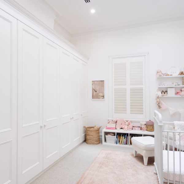 Traditional wall-to-wall Oxford wardrobe in Dulux Natural White 2-pack satin finish, custom-designed to seamlessly conceal a fireplace within the cabinetry.