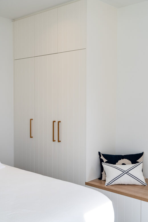 Modern Sorrento wardrobe with VVG rout in Dulux Natural White 2-pack satin, featuring a Polytec Natural Oak Matt bench seat and custom joinery by Packers.
