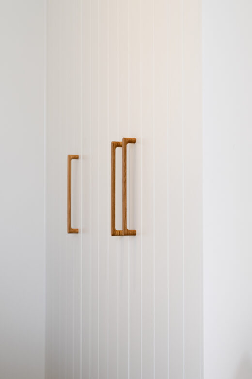 Modern Sorrento wardrobe with VVG rout detailing in Dulux Natural White 2-pack satin, featuring Kethy Pinta oak handles for a contemporary, textured finish by Packers.