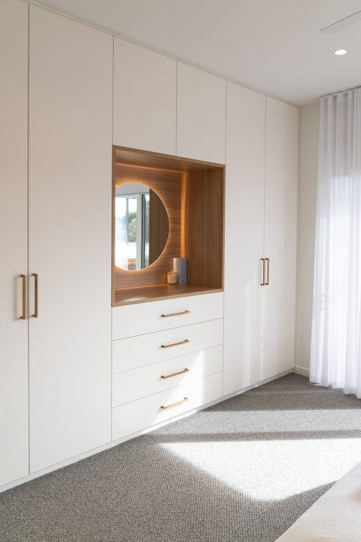 Modern Sorrento wardrobe and dresser in Vivid White 2-pack satin, featuring a back-lit LED mirror, exposed drawers, and a Polytec Natural Oak Matt benchtop with Kethy Pinta oak handles.