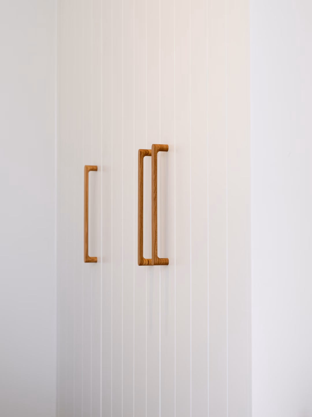 Modern Sorrento wardrobe with VVG rout detailing in Dulux Natural White 2-pack satin, featuring Kethy Pinta oak handles for a contemporary, textured finish by Packers.