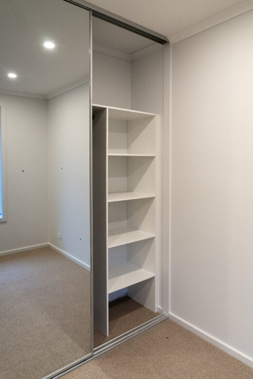 Halifax sliding wardrobe storage featuring a standard shelving unit and full-length mirror panel, custom-fitted for organised bedroom storage by Packers.