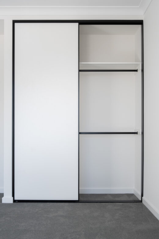 Modern two-door Halifax sliding wardrobe with white melamine panels and slimline black frames, featuring an internal double hang section for organised storage by Packers.