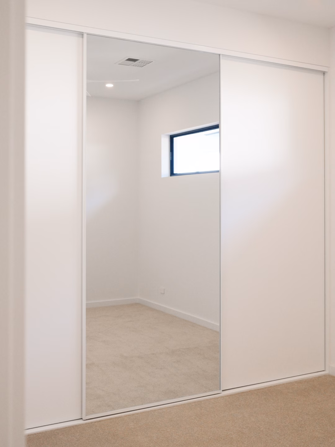 Modern Halifax sliding wardrobe combining Polytec Polar White Matt panels and full-length mirrors with slimline white frames, custom-installed by Packers.