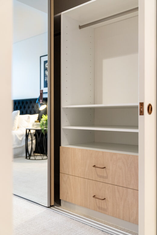 Internal Portsea sliding wardrobe featuring a custom drawer unit and hanging section behind a frameless mirrored door, precision-built by Packers.