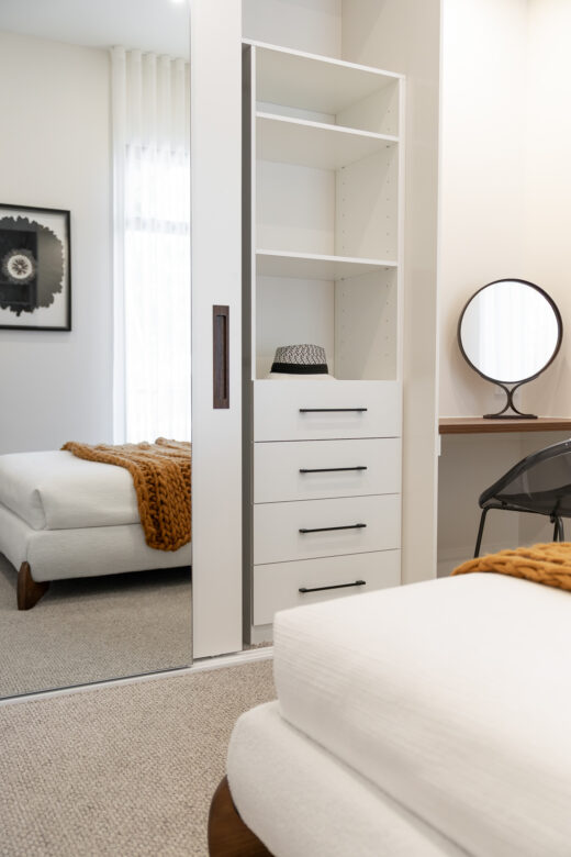 Bespoke bedroom joinery featuring a three-door wardrobe with a Portsea frameless mirror and Waterford framed door, integrated with a matching study desk and internal soft-close drawers by Packers.