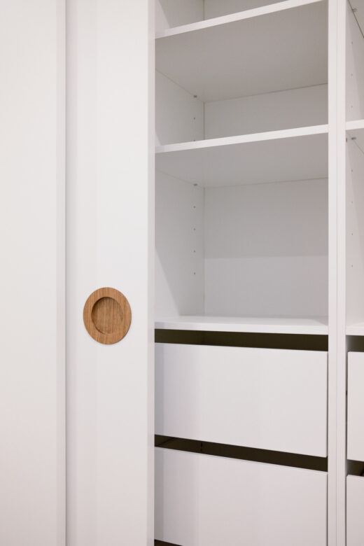 Close-up of a Waterford wardrobe door featuring an integrated timber handle and internal soft-close drawers with a finger gap design, custom-detailed by Packers.