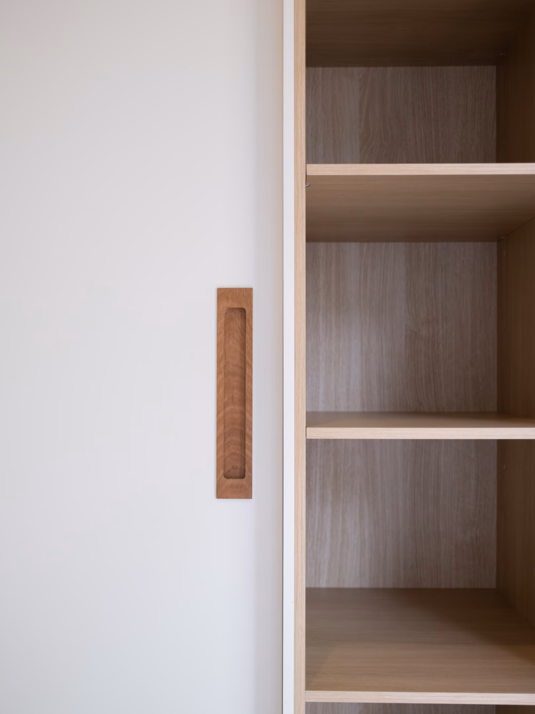 Custom Waterford wardrobe featuring American White Oak recessed timber handles and integrated open shelving, precision-crafted for a modern, functional bedroom design by Packers