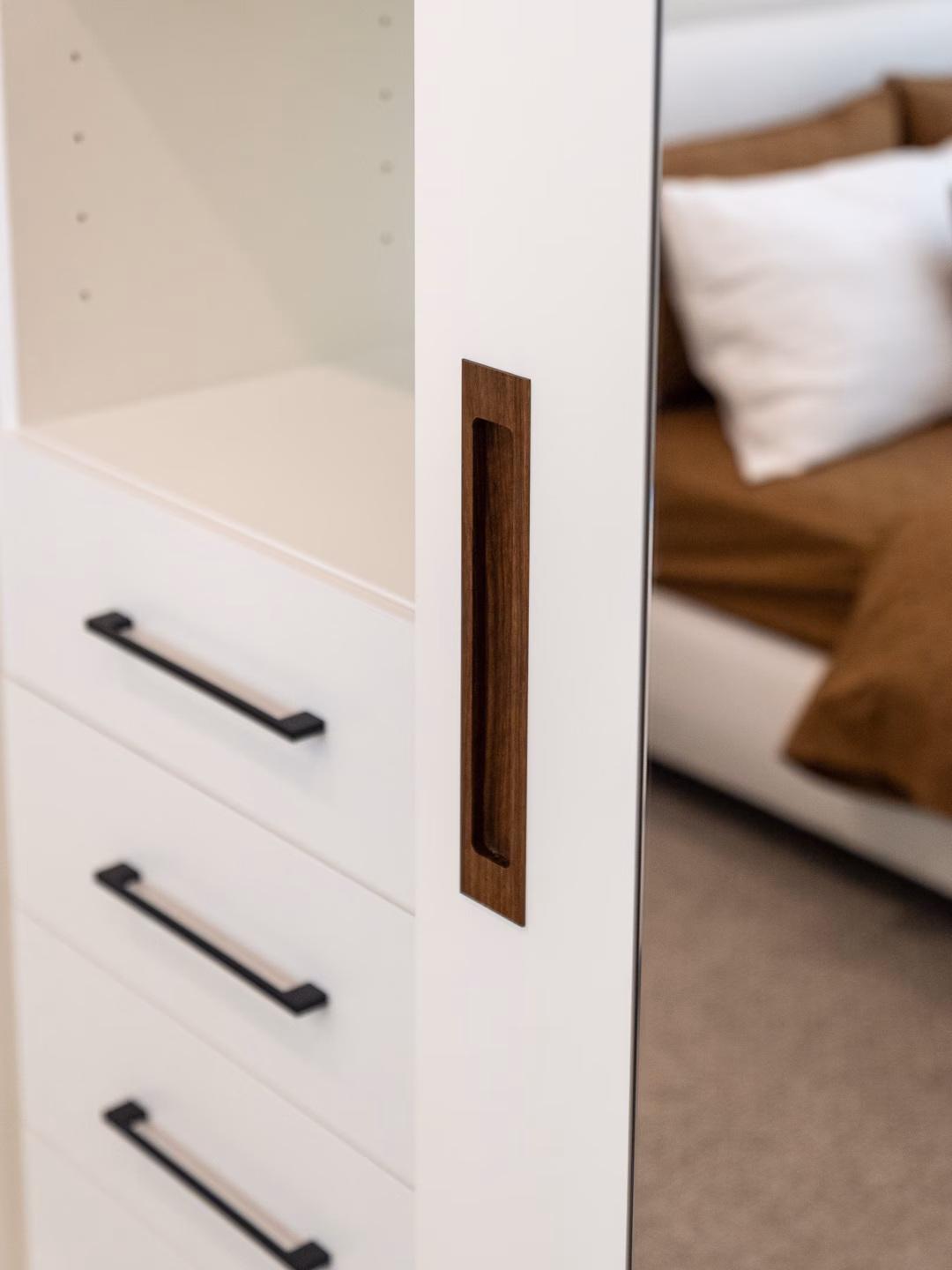 Close-up of a custom wardrobe featuring a handcrafted Spotted Gum recessed timber handle, integrated into a high-end cabinet door by Packers.