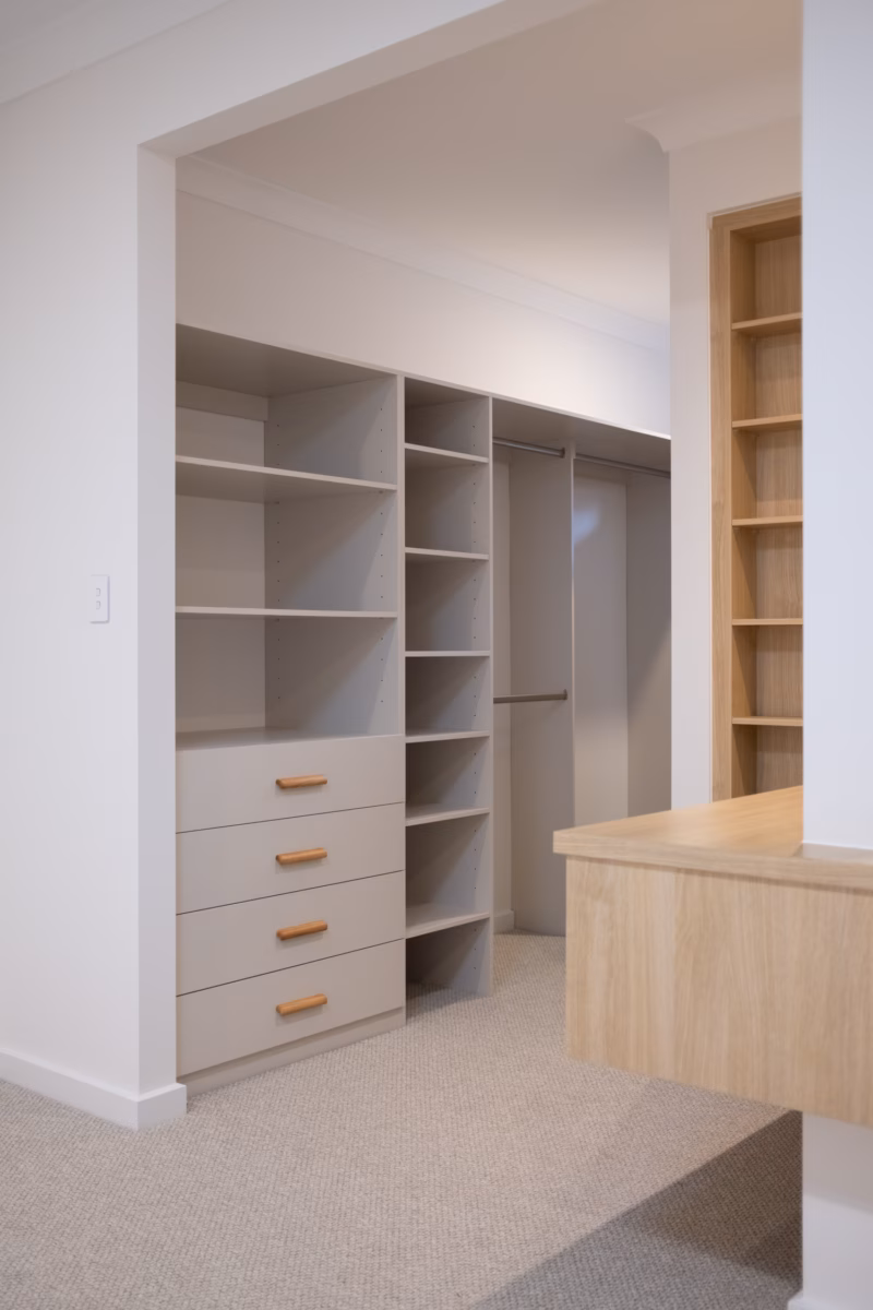Standard walk-in robe in Polytec Amaro Matt featuring a custom drawer unit with Furnipart Glove Oak handles positioned alongside a matching shoe tower, by Packers.