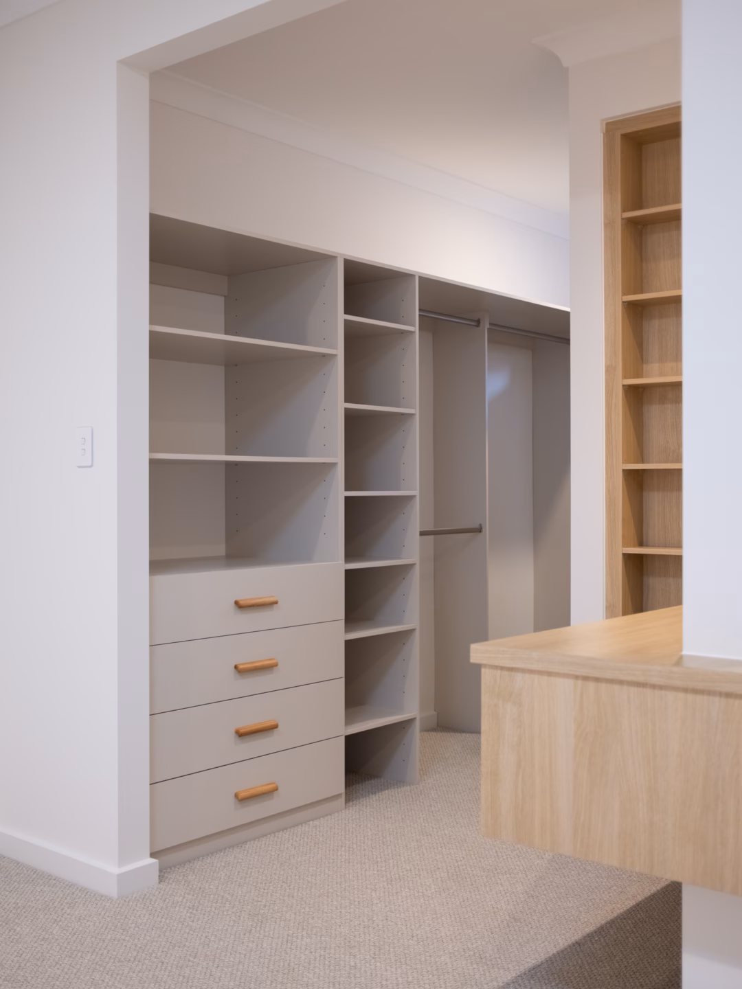 Standard walk-in robe in Polytec Amaro Matt featuring a custom drawer unit with Furnipart Glove Oak handles positioned alongside a matching shoe tower, by Packers.