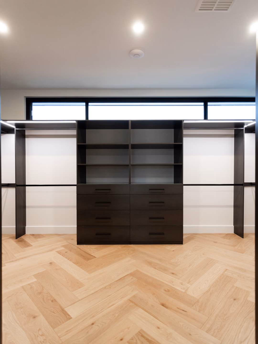 Standard walk-in robe custom-built in Polytec Empire Oak Matt featuring integrated Häfele LED lighting and slim-walled Alto drawer units, by Packers.