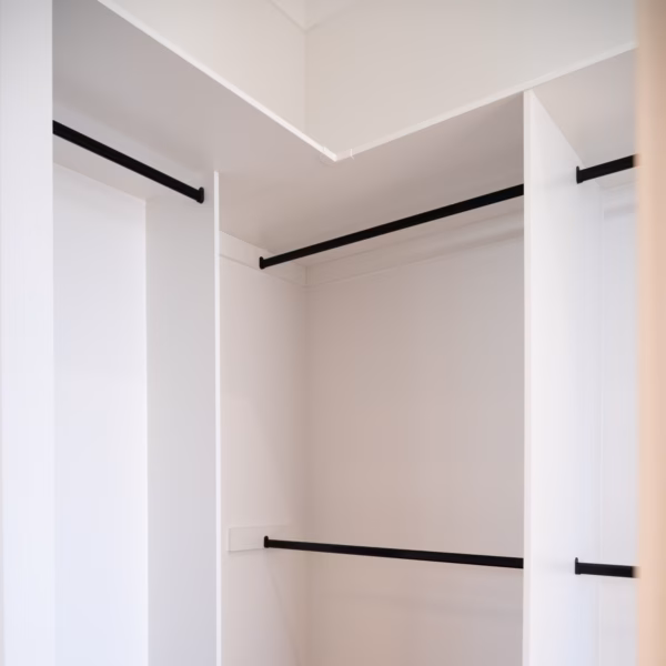 Standard walk-in robe in white melamine featuring a mix of long hanging and double hanging sections, with an accessible corner design and contrasting matte black hardware, by Packers.