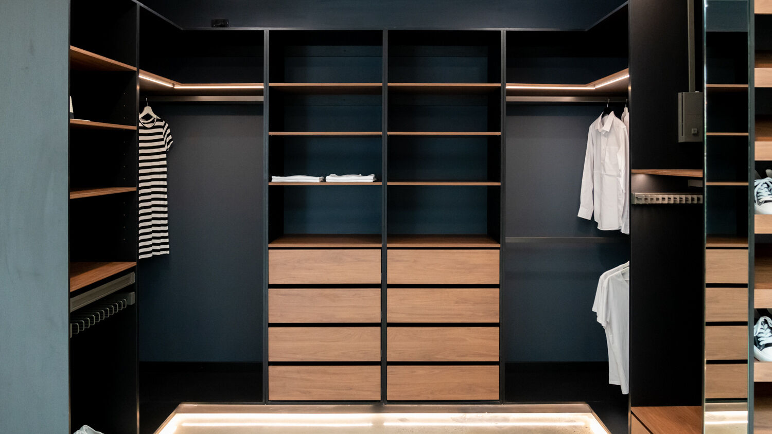 Semi-carcass walk-in robe featuring a sophisticated pairing of Polytec Black Woodmatt and Polytec Florentine Walnut Woodmatt for a high-end, architectural finish by Packers.