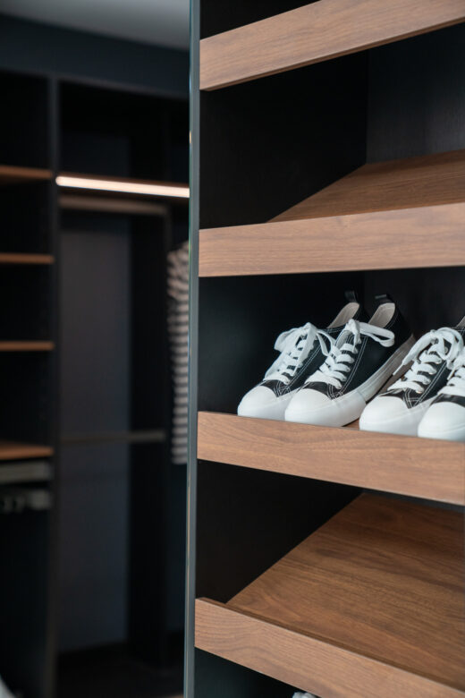 Close-up of custom angled shoe shelves in Polytec Florentine Walnut Woodmatt, showcasing a premium textured timber finish and organised footwear display by Packers.