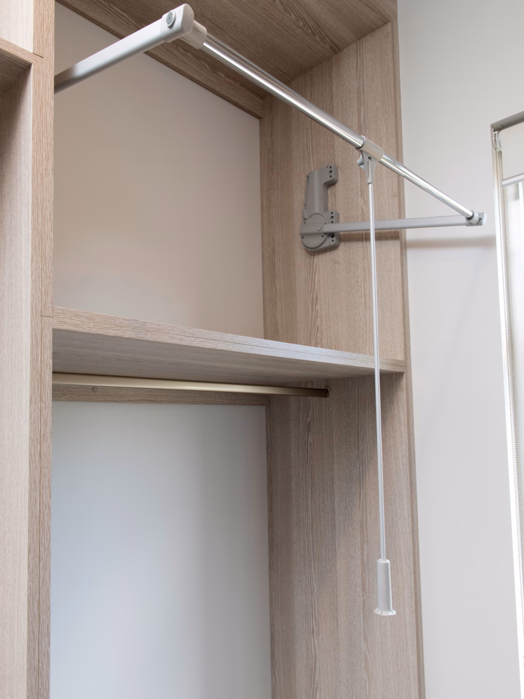 Standard walk-in robe featuring a Hettich pull-down hanging rail to maximise high ceilings, providing easy access to upper storage above lower hanging sections, by Packers.