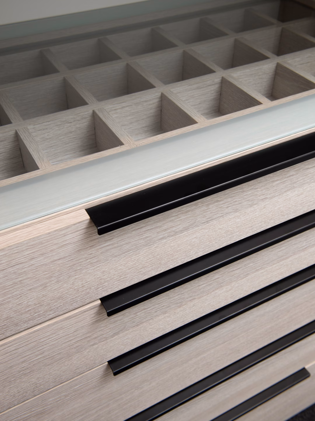 Semi-carcass walk-in robe featuring an etched glass top drawer unit with an integrated jewellery grid box and Artia Black Jay handles, custom-designed by Packers.