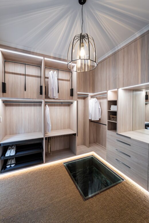 Luxury full carcass walk-in robe showroom display in Polytec Soft Walnut Ravine featuring Häfele Conero accessories, integrated LED lighting, and premium hinged overhead units, custom-built by Packers.
