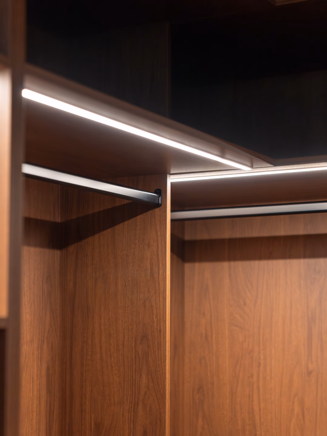 Close-up of a premium full carcass walk-in robe featuring integrated LED lighting, a matte black hanging rail, and custom-built cabinetry by Packers.