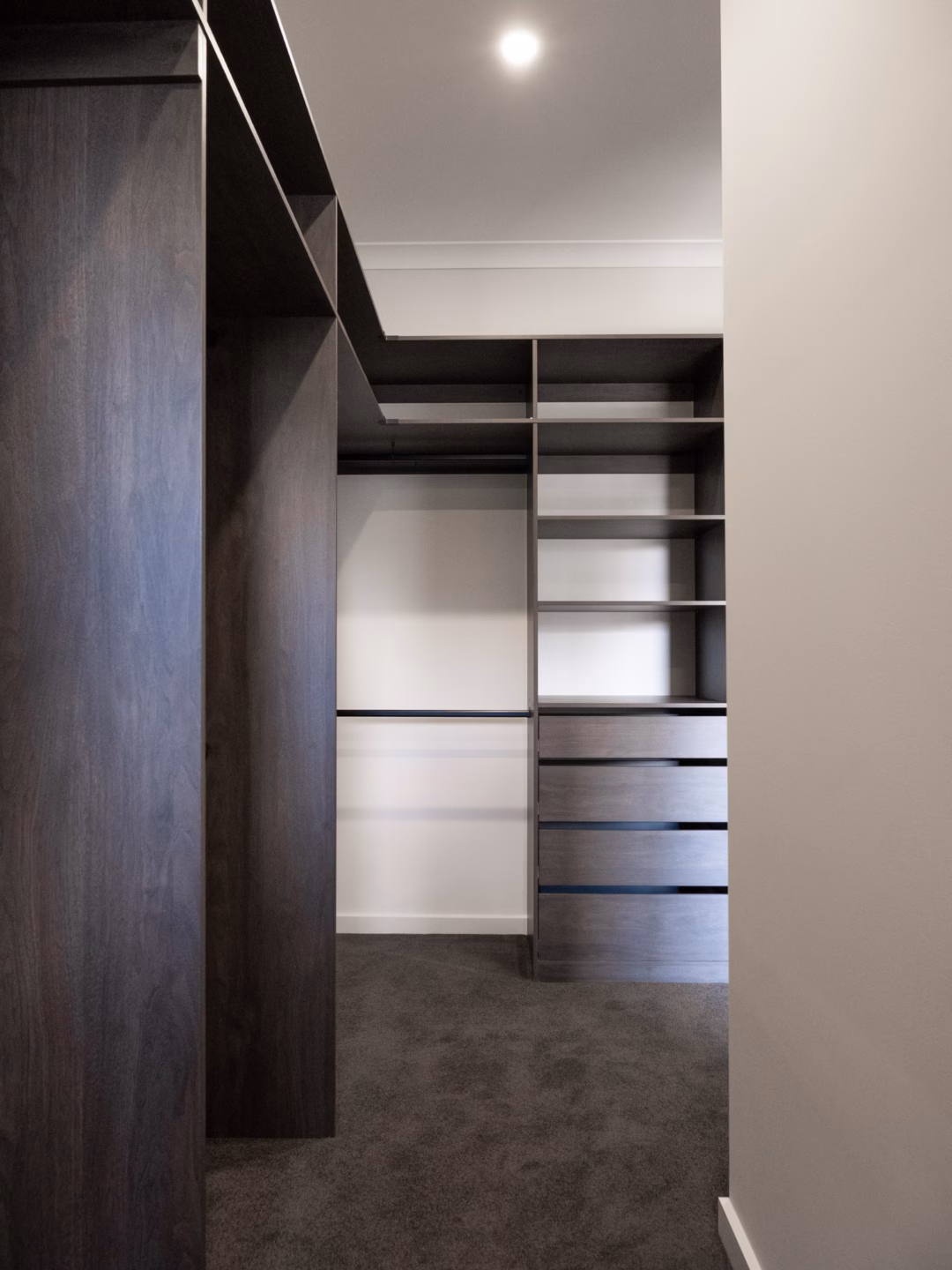 L-shaped standard walk-in robe featuring Polytec Perugian Walnut Woodmatt internals with a top shelf and upright configuration, custom-fitted by Packers.