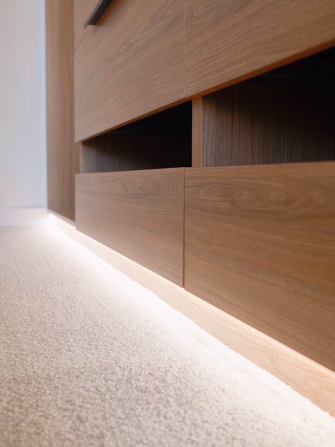 Close-up of a custom walk-in robe featuring pull-out shoe shelves and integrated LED kicker lighting in Polytec Tasmanian Oak Woodmatt, handcrafted by Packers.