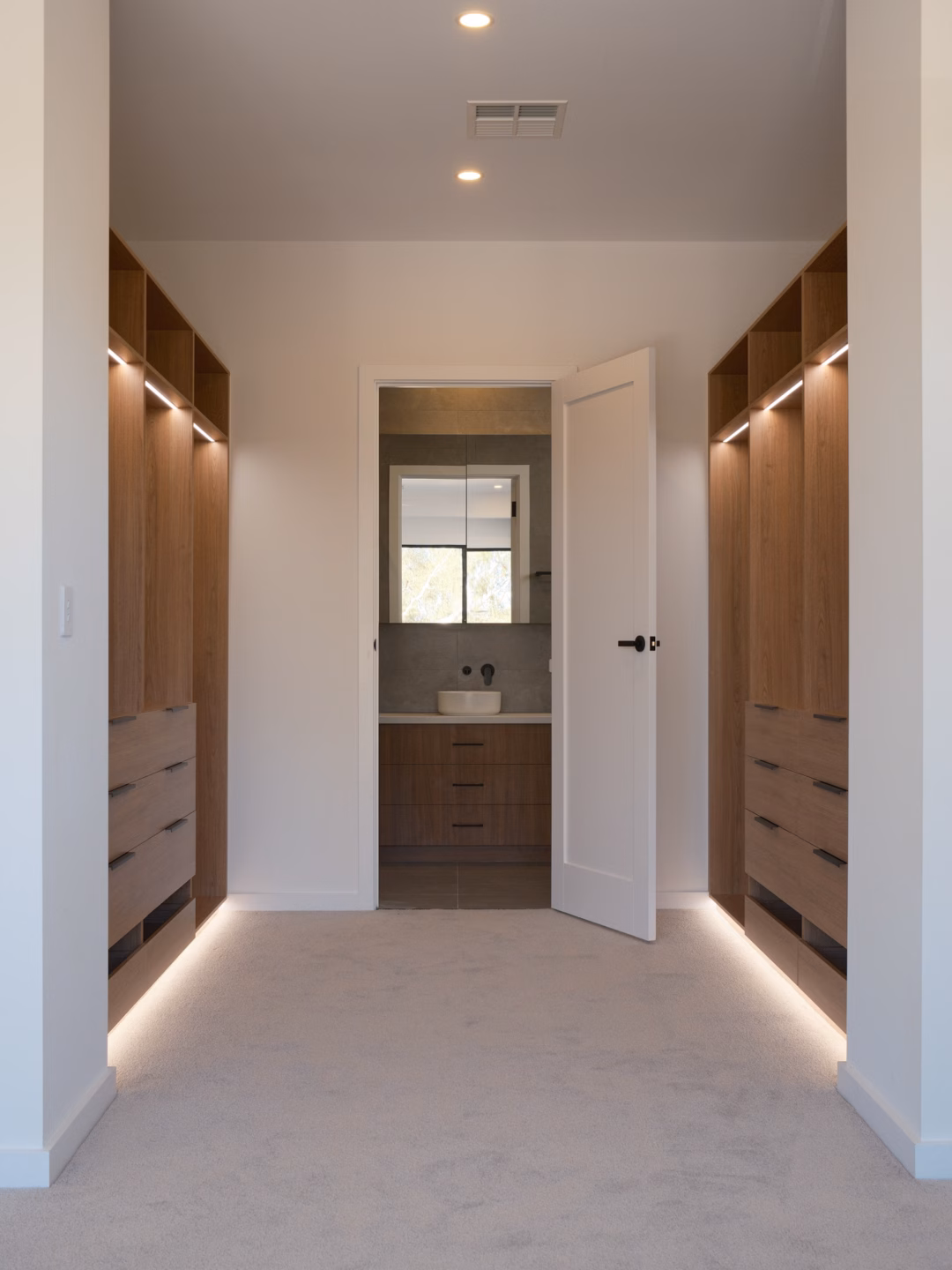 Custom semi-carcass walk-in robe in Polytec Tasmanian Oak Woodmatt featuring integrated Häfele LED lighting recessed into the kicker and top shelf, precision-built by Packers.